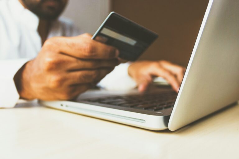 Person holding credit card in front of laptop